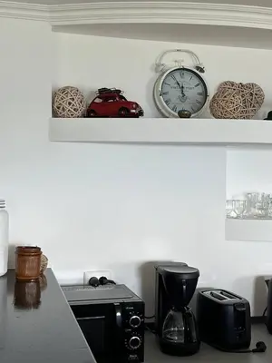 a counter with a microwave and a clock on a shelf at Taverna in São Jorge