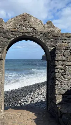 an arch in a stone wall near the ocean at Taverna in São Jorge