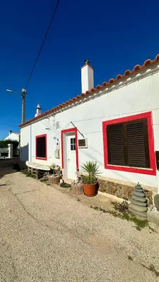 a white house with a red window and a door at Casa do Careca in Sagres