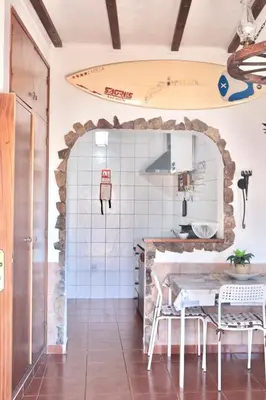 a kitchen with a table and a stone wall at Casa do Careca in Sagres
