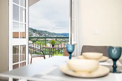a table with plates on it with a view of a balcony at Panoramic Attic by Sabugo House in Relógio do Poiso