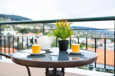 a table with two cups and a plant on a balcony at Panoramic Attic by Sabugo House in Relógio do Poiso