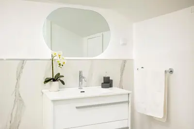 a white bathroom with a sink and a mirror at Panoramic Attic by Sabugo House in Relógio do Poiso