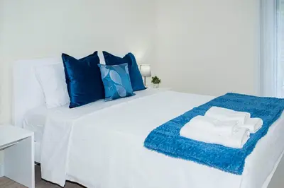 a white bed with blue pillows and towels on it at Panoramic Attic by Sabugo House in Relógio do Poiso