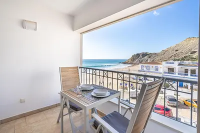 a balcony with a table and chairs and a view of the beach at Beach Apt 1 In Burgau in Burgau
