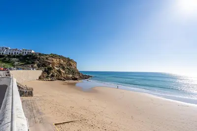 a beach next to the ocean on a sunny day at Beach Apt 1 In Burgau in Burgau