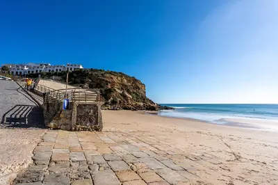 a sandy beach with a building and the ocean at Beach Apt 1 In Burgau in Burgau