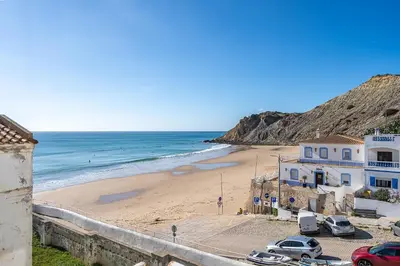 a beach with a white building and the ocean at Beach Apt 1 In Burgau in Burgau