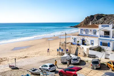 a beach with parked cars and a building and the ocean at Beach Apt 1 In Burgau in Burgau