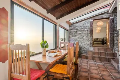 a dining room with a wooden table and chairs at Ocean View Eiras Cottage II in Fajã da Ovelha