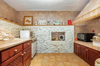 a kitchen with a stone fireplace in a room at Ocean View Eiras Cottage II in Fajã da Ovelha