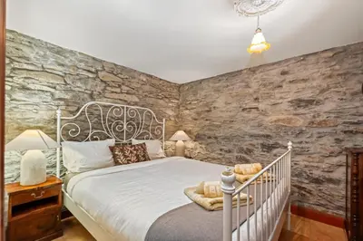 a bedroom with a bed and a stone wall at Ocean View Eiras Cottage II in Fajã da Ovelha