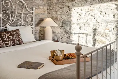a bedroom with a bed with a stone wall at Ocean View Eiras Cottage II in Fajã da Ovelha