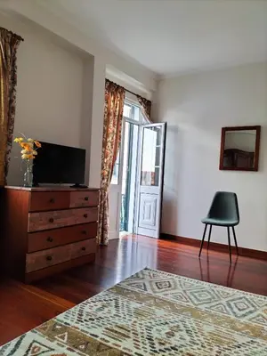 a living room with a television and a dresser and a chair at Hortasol B in Funchal