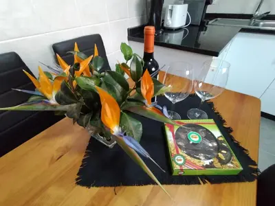 a table with a vase of flowers and wine glasses at Hortasol B in Funchal