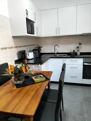a kitchen with a wooden table and white cabinets at Hortasol B in Funchal