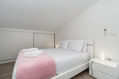 a white bedroom with a white bed and a pink blanket at Ana's View, cozy apartment, AC, sea view & parking in Arco da Calheta
