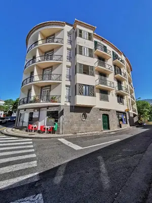 a large apartment building with red tables in front of it at NewCastle in Funchal