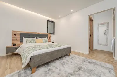a white bedroom with a large bed and a rug at Vienna apartment Alpine escape villa in Gaula