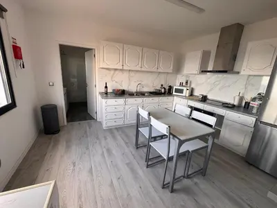 a kitchen with white cabinets and a table and chairs at LOV - Lombadinha Ocean View in Gaula