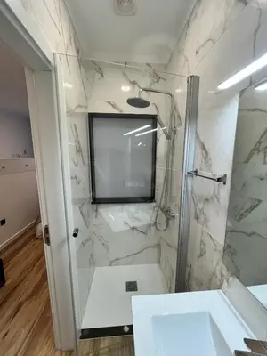 a bathroom with a shower with a television on the wall at Private 1 bedroom house in Machico Centre in Machico