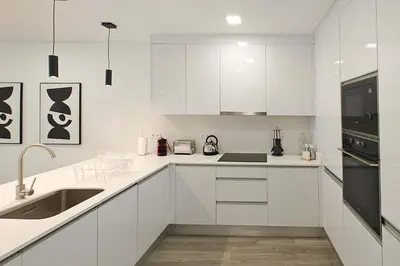 a white kitchen with white cabinets and black appliances at Holiday Beach in Machico