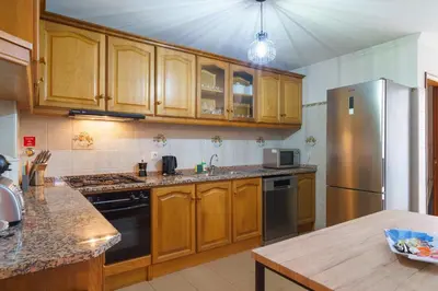 a kitchen with wooden cabinets and a stainless steel refrigerator at GuestReady - Breathtaking seaview in Caniço in Caniço