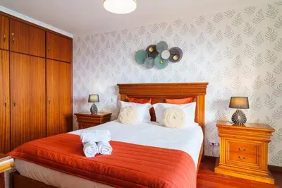 a bedroom with a large bed with red sheets and white towels at GuestReady - Breathtaking seaview in Caniço in Caniço