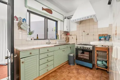 a kitchen with green cabinets and a sink and an oven at Burgau Fisherman's Cottage in Burgau