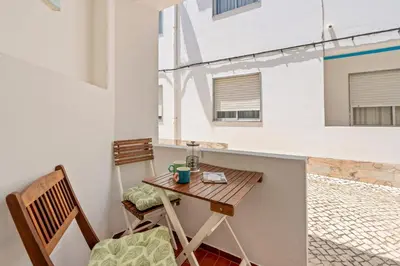 a small table and chairs in a room with a balcony at Burgau Fisherman's Cottage in Burgau