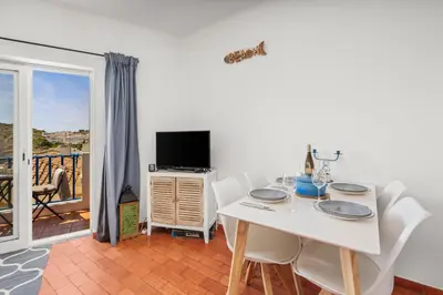 a dining room with a white table and chairs and a television at Casa Indie in Burgau
