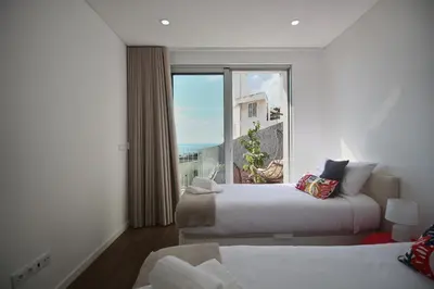 a hotel room with two beds and a large window at Like Home II - casa espaçosa com 3 quartos e vista mar in Funchal