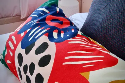 a colorful pillow sitting on top of a bed at Like Home II - casa espaçosa com 3 quartos e vista mar in Funchal