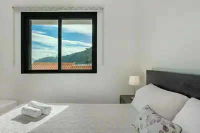 a white bedroom with a bed and a window at Apartamento Eden in Machico