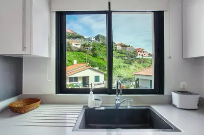 a kitchen with a sink and a large window at Apartamento Eden in Machico
