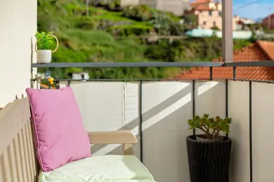 a chair on a balcony with a pink pillow at Apartamento Eden in Machico