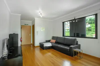 a living room with a black leather couch and a window at Apartamento Eden in Machico