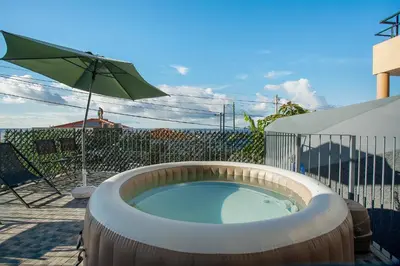 a hot tub with an umbrella on a patio at Casa Do Tempo com Jacuzzi in Ribeira Brava