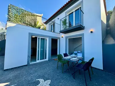 a patio with a table and chairs in front of a house at Casa Do Tempo com Jacuzzi in Ribeira Brava