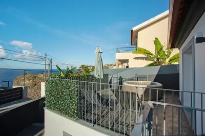 a balcony with a table and an umbrella on it at Casa Do Tempo com Jacuzzi in Ribeira Brava
