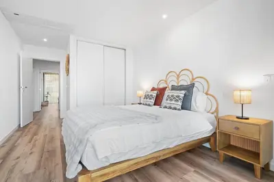 a white bedroom with a large bed with a wooden headboard at Peace Haven III in Câmara de Lobos