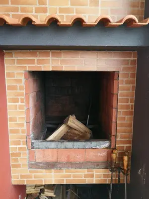 a brick fireplace with a pile of wood in it at House in the montain Casa do Cabeço in Machico