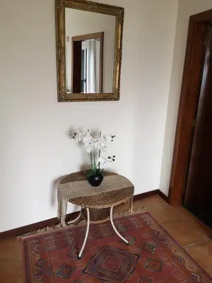 a table with a vase of flowers on it with a mirror at House in the montain Casa do Cabeço in Machico