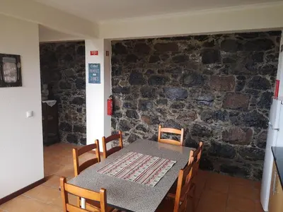 a table and chairs in a room with a stone wall at House in the montain Casa do Cabeço in Machico
