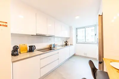 a white kitchen with white cabinets and a table at Formosa Stay IV by YOUR KEY in Funchal