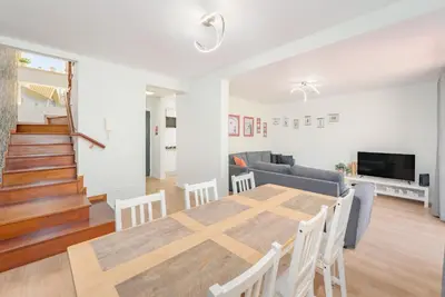 a dining room and living room with a table and chairs at Madeira Dreams in Caniço