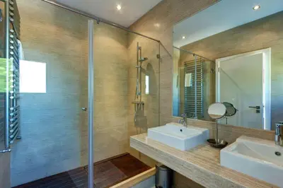 a bathroom with a sink and a shower and a mirror at Jacaranda Beach Villa in Luz