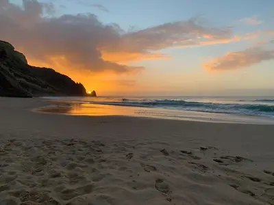 a sunset on a beach with the ocean at Jacaranda Beach Villa in Luz