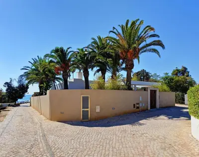a house with palm trees behind a fence at Jacaranda Beach Villa in Luz