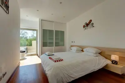 a bedroom with a large white bed and a window at Jacaranda Beach Villa in Luz